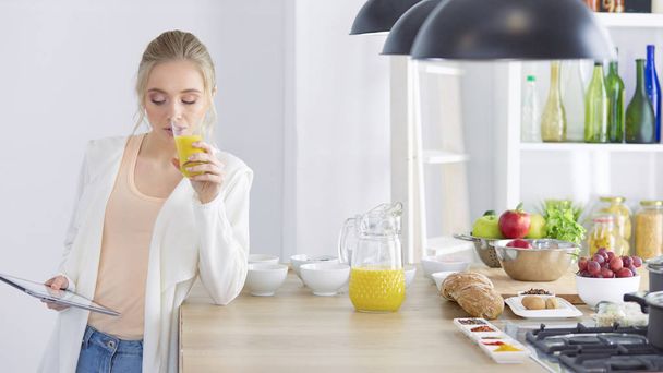 gyönyörű fiatal nő használ egy digitális tabletta a konyhában - Fotó, kép