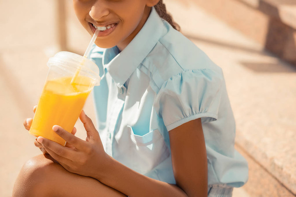 Pretty international little female enjoying orange juice - Фото, изображение