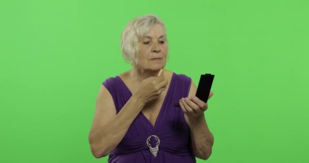 An elderly woman makes makeup. Old pretty grandmother. Chroma key - Footage, Video