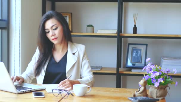 Запись 4К, занятая деловая женщина, работающая с ноутбуком, пишущая на книге и мыслящая с серьезным лицом на рабочем месте, образ жизни деловых людей. Азиатская модель, 30 лет
 - Кадры, видео