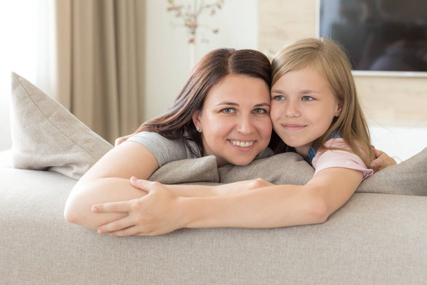 ソファに座っている母と十代前の娘が微笑んでいる。ハッピーファミリーコンセプト - 写真・画像