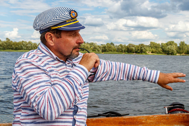 空とワットに対して帆の下でボートの帽子をかぶった船員の男 - 写真・画像