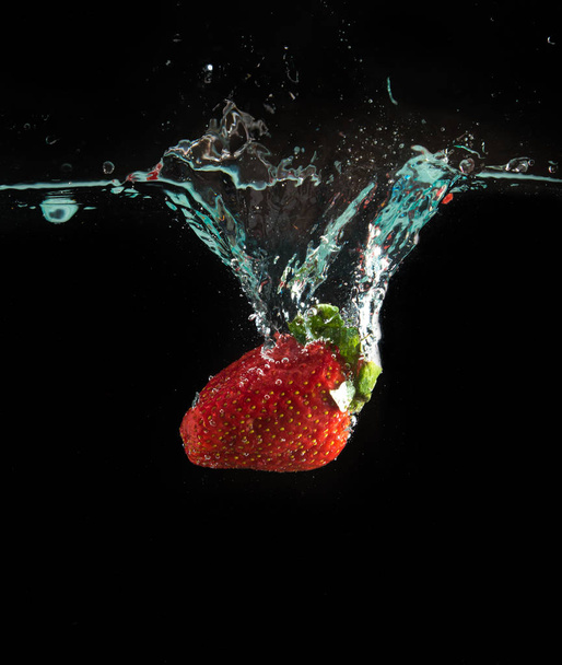 Strawberri splashing into water on the black - Foto, imagen