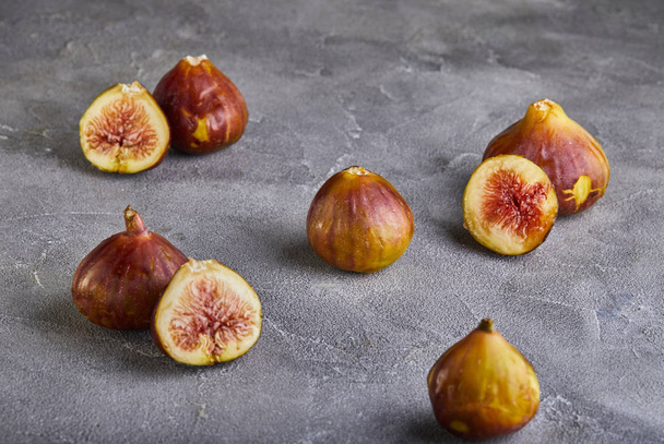 Fresh figs whole and cut into pieces on a gray background, the concept of a healthy - Photo, Image
