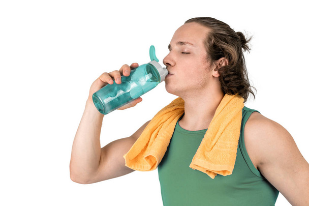 Handsome young man in sport shirt holding bottle of water. White background isolated - 写真・画像