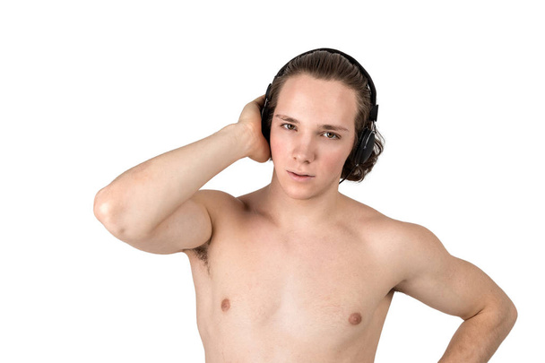 Handsome naked young man in towel listening to music in headphones on white background isolated - Foto, Bild