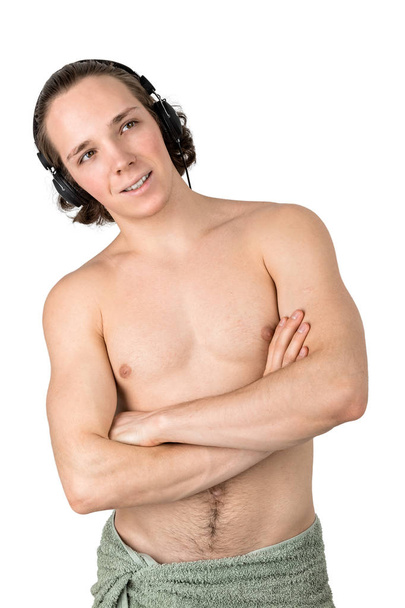 Handsome naked young man in towel listening to music in headphones on white background isolated - Valokuva, kuva