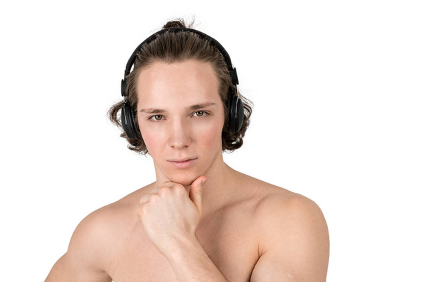 Handsome naked young man in towel listening to music in headphones on white background isolated - Fotografie, Obrázek
