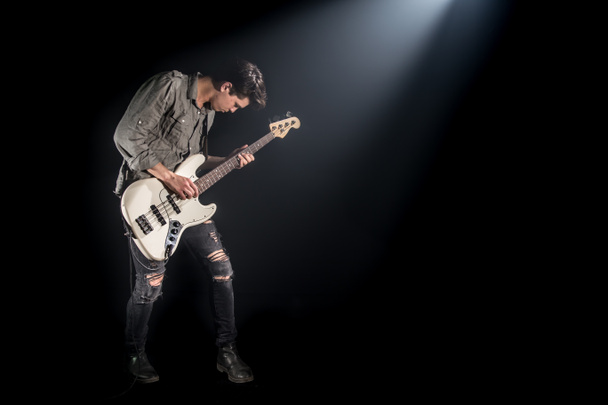 der Musiker spielt Bassgitarre, auf schwarzem Hintergrund mit Bea - Foto, Bild