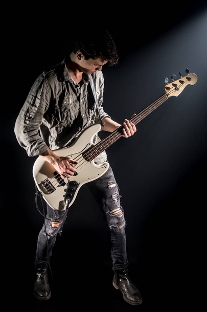 the musician plays bass guitar, on a black background with a bea - Photo, Image