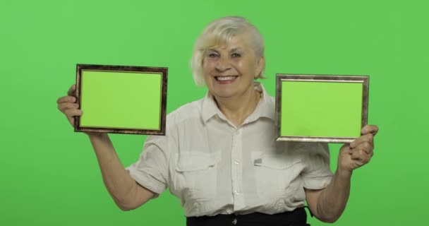 Una donna anziana con due cornici con un'immagine verde. Nonna. Chiave cromatica
 - Filmati, video