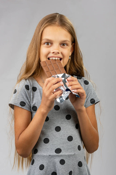 On yıl kız çikolata ısırır ve mutlu çerçeveye bakıyor - Fotoğraf, Görsel