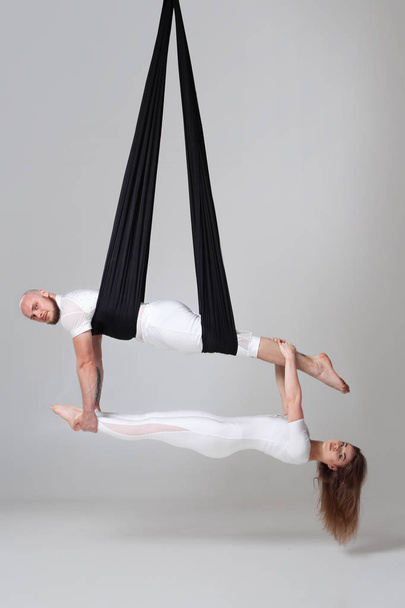 Hermosa chica y un hombre atlético en un traje deportivo blanco están realizando un acrobático elementos en un estudio
. - Foto, imagen