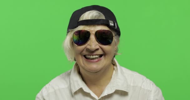 Uma idosa de óculos de sol e boné sorri. Velha avó. Chave Chroma
 - Filmagem, Vídeo