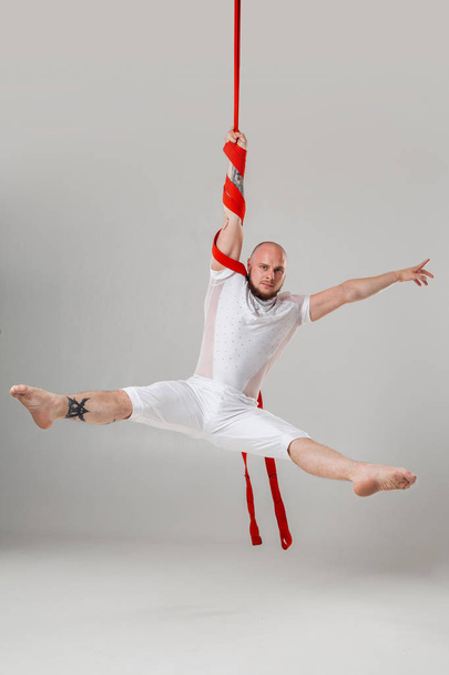 Спортсмен у білому спортивному костюмі виконує акробатичні елементи в студії
. - Фото, зображення