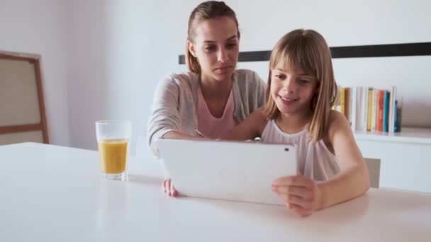 Pretty young mother and her daughter using digital tablet at home. - Metraje, vídeo