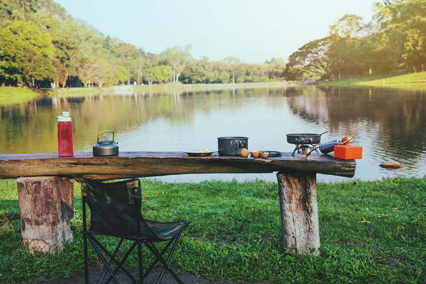 Tło puli i piknik gazowy, który jest umieszczony na stole drewniany. Camping, piknik, gotowanie, jedzenie nad jeziorem. - Zdjęcie, obraz