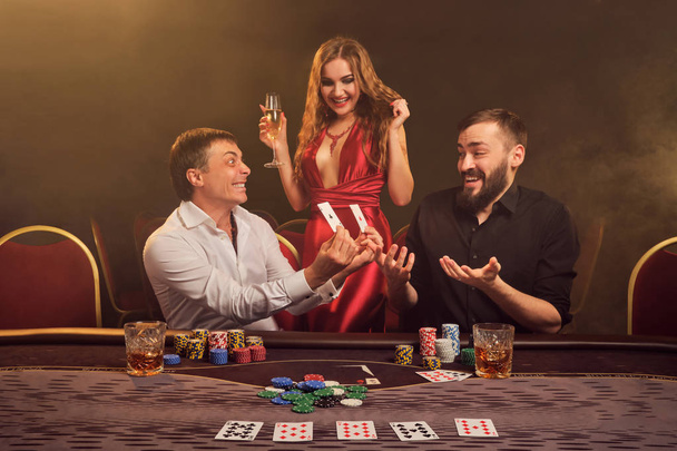 Groep van een jonge rijke vrienden spelen poker in een casino. - Foto, afbeelding