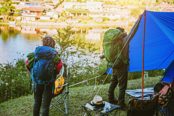 Casal Apreciando Camping Holiday In Countryside.Camp nas montanhas perto do lago. Ajuda a acampar a tenda
 - Foto, Imagem