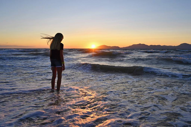 Mladá dívka na pláži u moře při západu slunce. - Fotografie, Obrázek