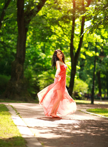 Joyful young woman enjoys dancing in green city park on nature - Foto, afbeelding