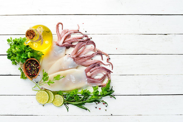 Raw fresh squid with spices. Seafood on a white wooden background. Top view. Free copy space. - Φωτογραφία, εικόνα