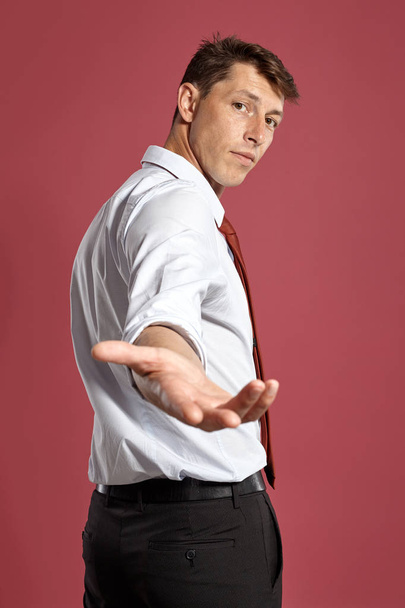 Πορτρέτο ενός νεαρού Μπρουνέ άνθρωπος που ποζάρει σε ένα στούντιο σε ένα κόκκινο φόντο. - Φωτογραφία, εικόνα