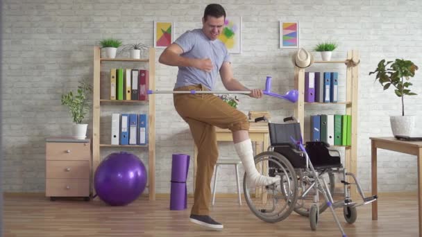 man met een gebroken verbonden been speelt krukken als een gitaar slow mo - Video
