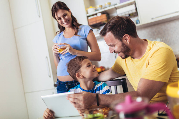 Donna incinta e la sua famiglia a colazione in cucina
 - Foto, immagini
