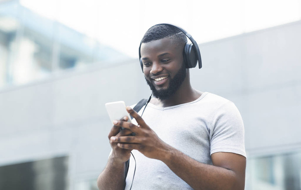 Afrykański facet w słuchawkach wybiera swoją ulubioną playlistę - Zdjęcie, obraz