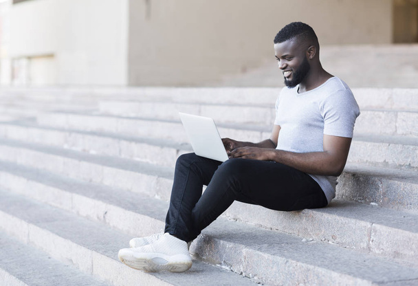 African American Freelancer werkt op een laptop zittend op trappen - Foto, afbeelding