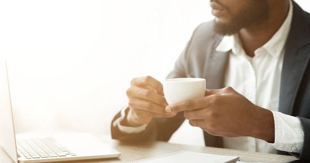 nachdenklicher Afro-Geschäftsmann trinkt Kaffee am Arbeitsplatz - Foto, Bild