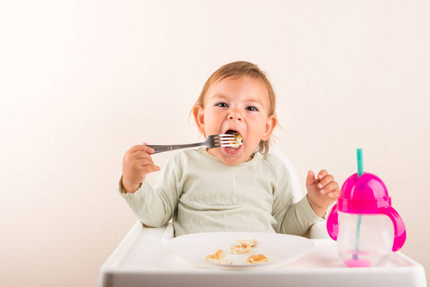 Baby toddler eating pancakes with fork. Isolated. Copy space - Foto, afbeelding