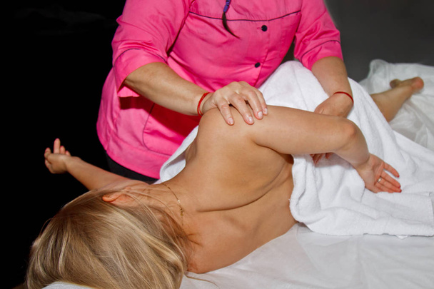 professional therapeutic massage. girl the athlete in a massage room. body and health care. pain recovery procedure. Female physiotherapist doing manipulative spine treatment on young patient - Valokuva, kuva