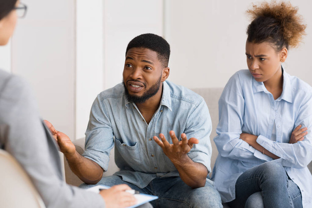 Afro-Amerikaanse man praten met psycholoog zittend naast vrouw - Foto, afbeelding