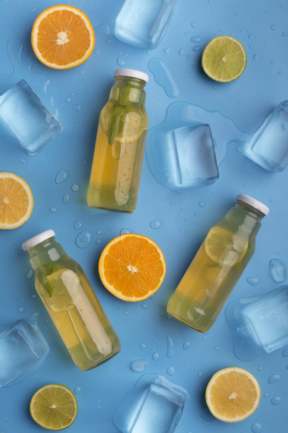 Zomer detox limonade met vers fruit en ijsblokjes op blauw - Foto, afbeelding