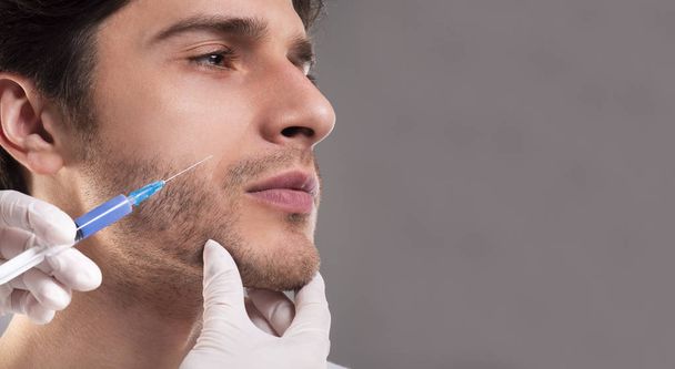Young man getting anti aging injection in jaw - Foto, Bild