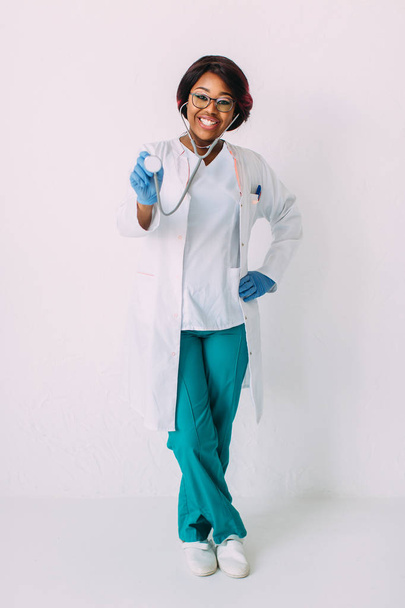 聴診器を持つ白いコートを着た若い笑顔のアフリカ系アメリカ人女性医師 - 写真・画像