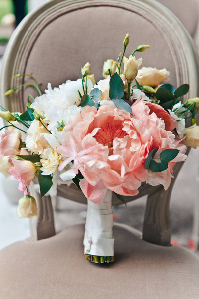 Close-up bridal bouquet of fresh spring and summer flowers in pastel colors stand on a classic chair, selective focus - Photo, image