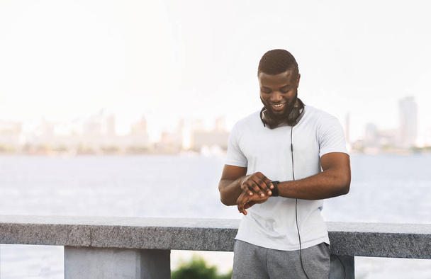 Sporty black guy checking heart rate on smartwatch and smiling - Photo, Image