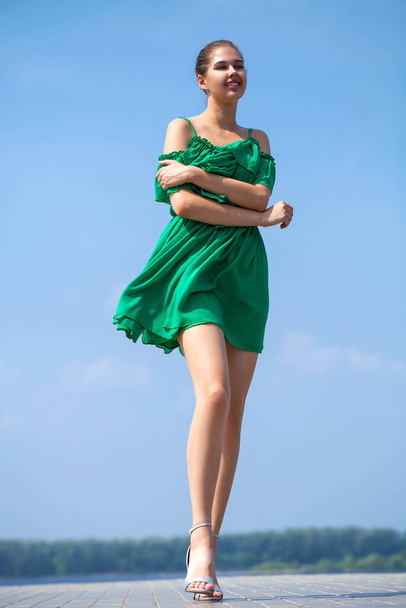 Young beautiful woman in green dress walking on the summer stree - Photo, image