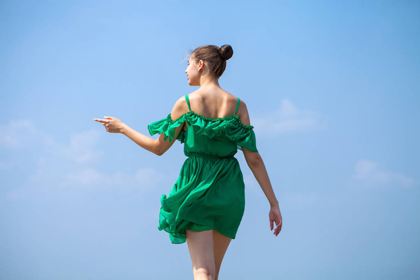 Young beautiful brunette girl in green dress walks along the emb - 写真・画像