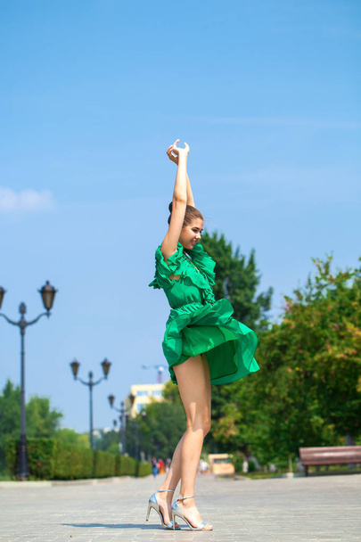 Young beautiful woman in green dress walking on the summer stree - 写真・画像