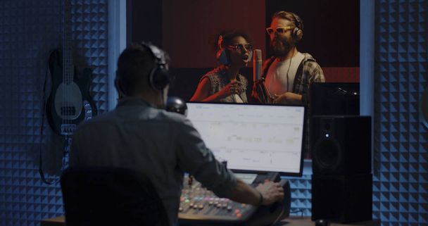 Singers and sound engineer working in studio - Foto, imagen