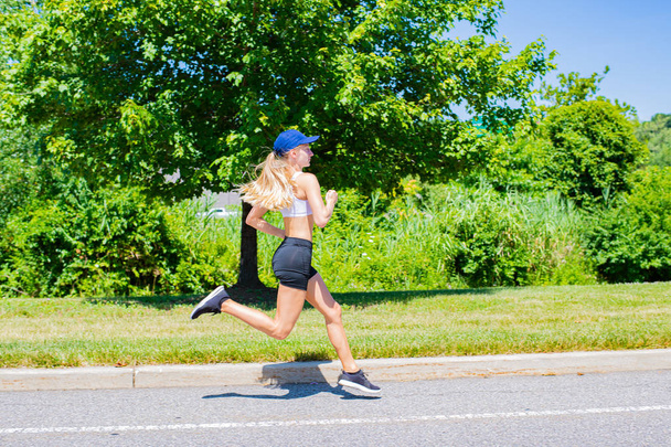 Sporty woman in sportswear trail running on the road. Athlete girl is jogging in the park. - Φωτογραφία, εικόνα