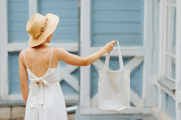Woman with cotton bag near blue wall. Mockup for design. Reusable eco bag for shopping. Zero waste concept. - Foto, imagen
