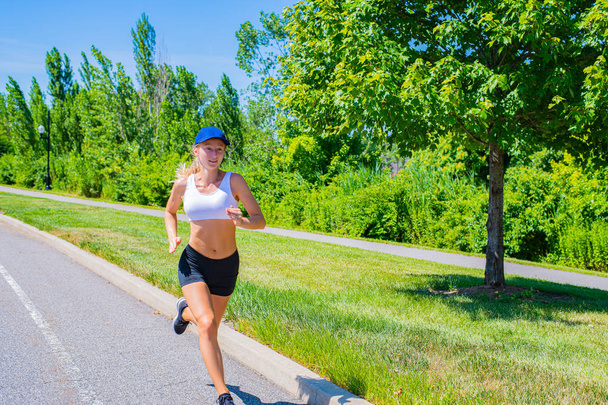 Sporty woman in sportswear trail running on the road. Athlete girl is jogging in the park. - Φωτογραφία, εικόνα