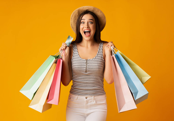 Joven alegre sosteniendo coloridas bolsas de compras y tarjeta de crédito
 - Foto, imagen
