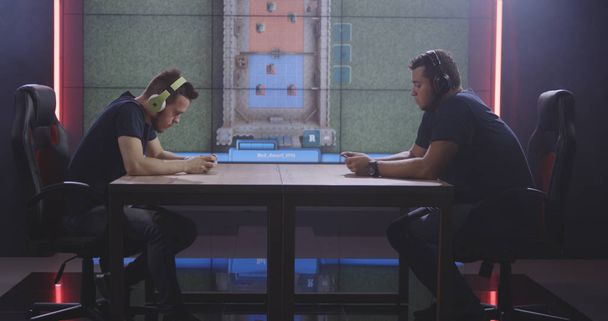 Двое мужчин играют в мобильную игру на турнире
 - Фото, изображение