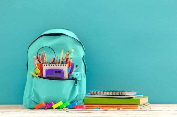 Full blue School Backpack with different supplies on blue background. Concept back to school - Foto, afbeelding